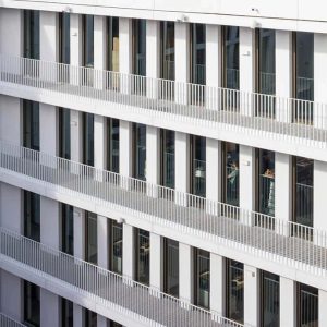 Detailaufnahme einer modernen Fassade mit weißen Balkongeländern, großen Fenstern und klaren Linien.