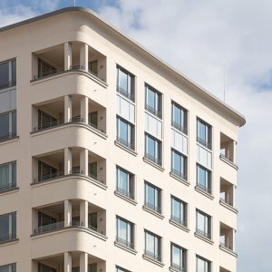 Nahaufnahme einer modernen Gebäudefassade mit abgerundeten Balkonecken und großen Fenstern in symmetrischer Anordnung.