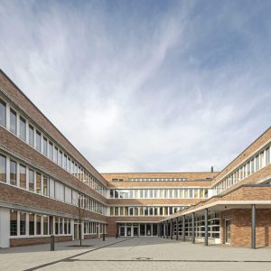 Langes Ziegelgebäude mit zahlreichen Fenstern und einem Innenhof