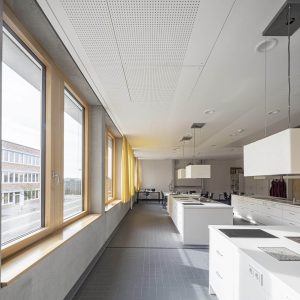 Lichtdurchfluteter, weitläufiger Raum mit Holzfenstern und modernen Kochfeldern mit Spülbecken.